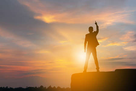 Silhouette of Business Engineer Man Celebration Success Happiness on a Stone Evening Sky Sunset Background, Sport and active life Concept.の写真素材