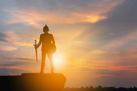 Silhouette of Businessman Knight Sword and Shield in Sunset Background, Fighting Business Warrior Concept.の写真素材