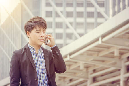 Close up of young business man using mobile smartphone outside office blurry backgroundの写真素材
