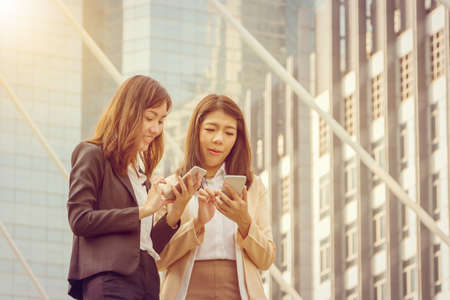 Portrait of beautiful casual business woman using smartphone outside office in the city backgroundの写真素材