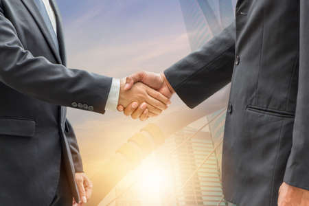 Success and Happiness Team Concept Business man handshake, Double exposure photo of city view at sunrise background.の写真素材