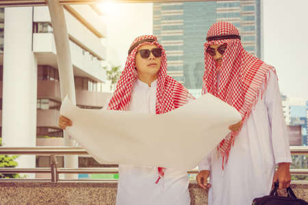 Close up of young Arab Middle Eastern Business man team holding drawing paper in hand against city background planing and management concept.の写真素材