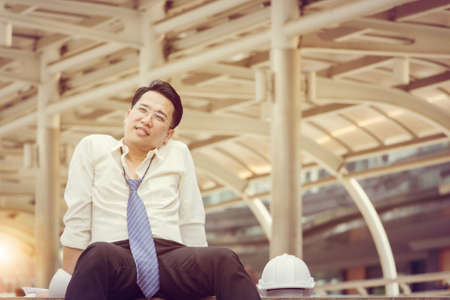Business engineering man relaxing lying and sitting on the floor after working hardの写真素材