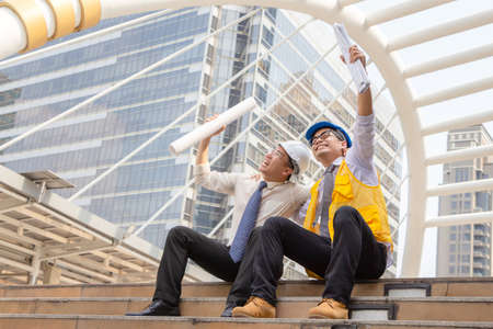 Success and Happiness concept, Business engineer man holding drawing paper in hand at city outside...