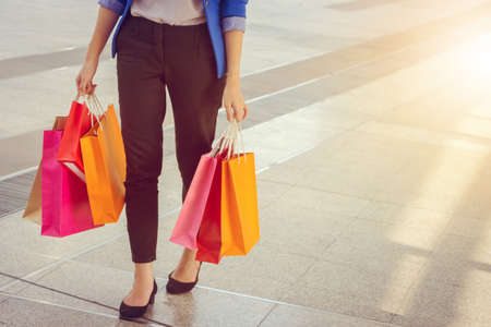 Close-up of young woman carrying shopping bags while walking along the street. Happy Life Style Concept.の写真素材