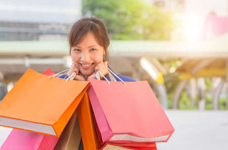 Close-up of young woman carrying shopping bags while walking along the street. Happy Life Style...