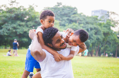 Cheerful african american father and two sons playing in park, Happiness family concepts, parent and childs play in parkの写真素材