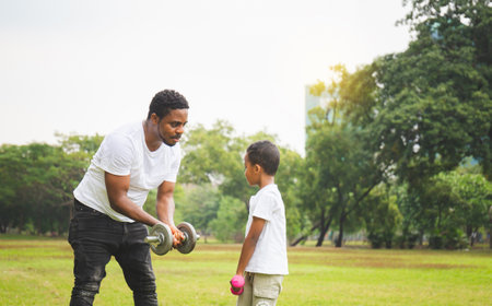Cheerful african american father and son playing exercising with dumbbell in park, Happiness family conceptsの写真素材