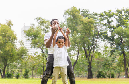 Cheerful african american father and son playing exercising with dumbbell in park, Happiness family conceptsの写真素材