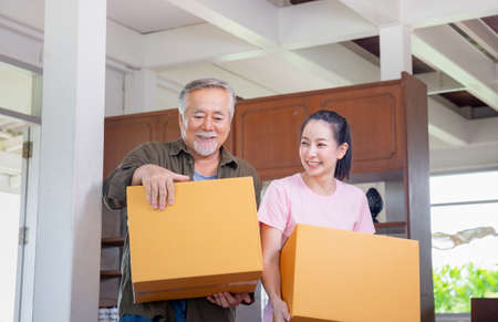 Young daughter and senior father carrying boxes into new home, Happiness family on moving day conceptsの写真素材