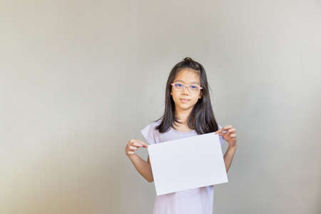 Asian girl with white sheet of paper, girl holding empty blank paper, mock up blank sign for message creative design concepts.の写真素材