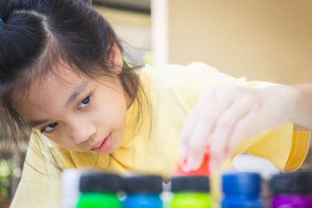 Asian little girl looking and pouring red ink to palette, Creativity children conceptsの写真素材