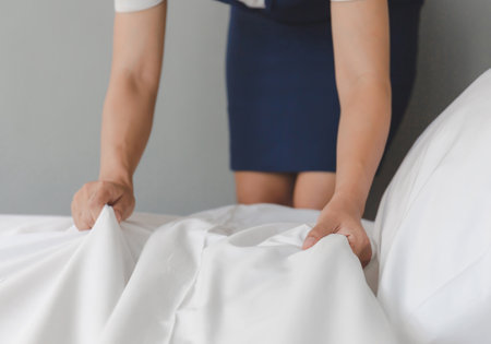 Close up of Hotel room service hands making bed, female maid making bed in hotel roomの写真素材