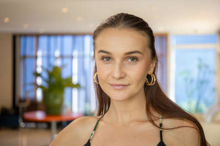 Headshot portrait of smiling woman looking at camera, happy girl with cute pretty face posing indoorsの写真素材
