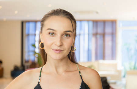 Headshot portrait of smiling woman looking at camera, happy girl with cute pretty face posing indoorsの写真素材