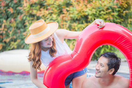 Cheerful young friends having fun in heart shaped inflatable, Happy young couple having fun at swimming pool. Happiness lifestyle conceptsの写真素材