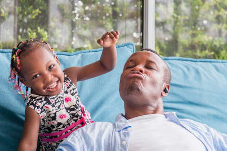 Cheerful african american father and daughter playing in living room, Happiness family conceptsの写真素材