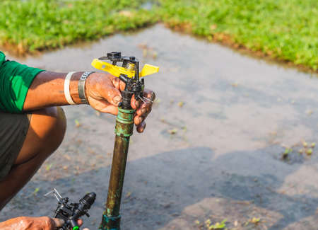 Man fixing automatic sprinkler in the green field for reducing water in the farm , irrigation systemの写真素材