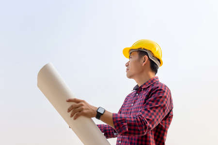 Engineer man holding blueprint checking and planning project at construction site, Man holding blueprint and looking into the skyの写真素材
