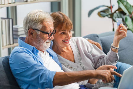 Happy senior couple shopping online in living room, Elderly woman and a man using computer laptop on...