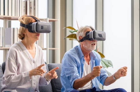 Senior mature couple sitting on the sofa having fun with virtual reality glasses, Happy elderly technology conceptsの写真素材