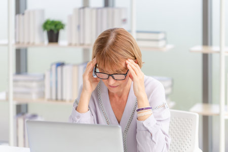 Unhealthy mature woman touch forehead suffers from migraine strong headache, woman massaging temples close up, suffering from strong head acheの写真素材
