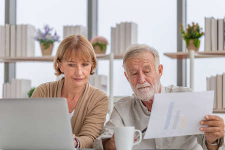 Worried senior couple checking their bills, retired elderly old family reading documentsの写真素材