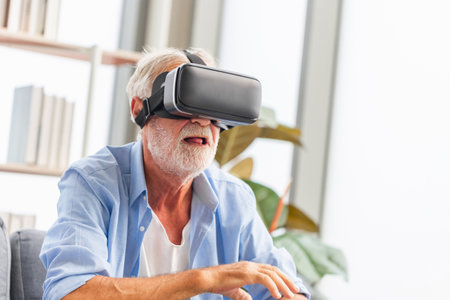 Senior man sitting on the sofa having fun with virtual reality glasses, Happy elderly technology conceptsの写真素材