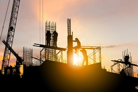 Silhouette of Engineer and worker with clipping path checking project at building site background, construction site at sunset in evening timeの写真素材