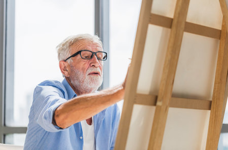 Senior man painting on canvas at home, Elderly man painting on a canvas, Happy retirement concepts