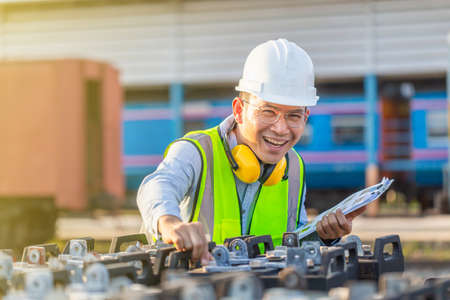 Engineer in waistcoats and hardhats with documents inspecting construction site, Smiling mechanical worker checking of the battery storage systemの写真素材