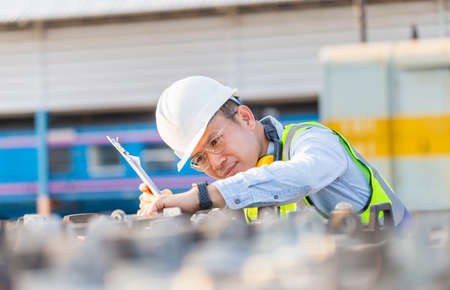 Engineer in waistcoats and hardhats with documents inspecting construction site, Smiling mechanical...