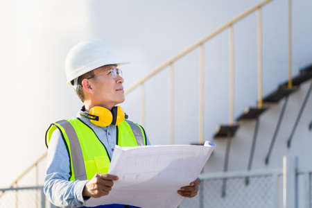 Engineer under inspection and checking oil storage tank, Engineer man in waistcoats and hardhats and...
