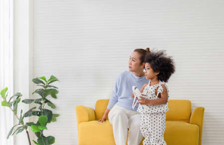 Little kid girl and grandmother playing cheerfully in living room, grandmother and child looking...