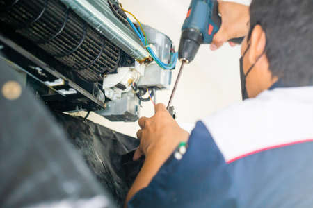 Selective focus on dirty inside compartments air conditioner, Male technician fixing air conditioner indoors, Maintenance and repairing conceptsの写真素材