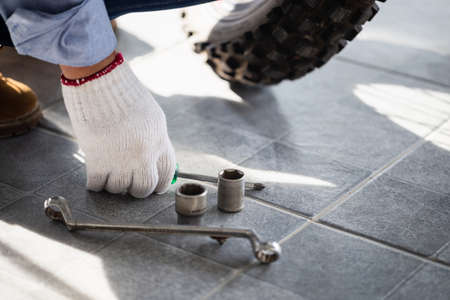 Close-up of Young man hand fixing motorcycle, Man repairing motorcycle in a repair shop, Mechanic holding screwdriverの写真素材