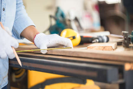 Carpenter working with equipment on wooden table in wood workshop, man doing woodwork in carpentry...