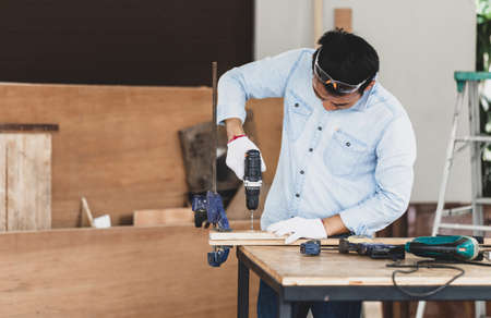 Carpenter working in wood workshop, Craftsman with drill in electric screwdriver, Man holding electric screwdriver drill, Male doing woodwork in a workshopの写真素材