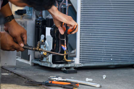 Air Conditioning Repair team use fuel gases and oxygen to weld or cut metals, Oxy-fuel welding and oxy-fuel cutting processes, repairman on the floor fixing air conditioning systemの写真素材