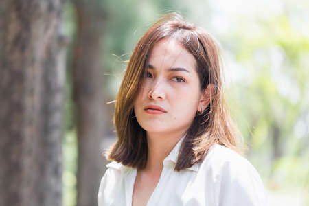 Head and shoulders portrait of serious young woman, sad woman in the parkの写真素材