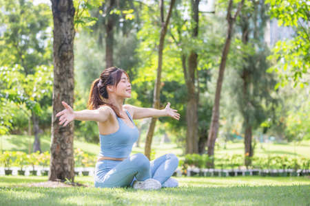 Sport woman breathing deeply fresh air with arms raised outdoor in parkの写真素材