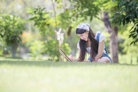 Beautiful teenage girl drawing a picture in the park with easel, palette and paintbrush