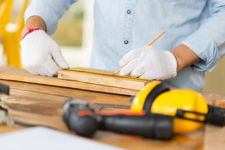 Carpenter working with equipment on wooden table in wood workshop, man doing woodwork in carpentry shopの写真素材