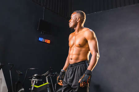 Sport and fitness concepts, Young man standing strong in gym and flexing muscles