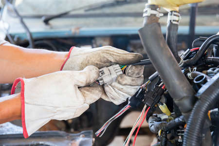 Auto mechanic doing car service and maintenance. Car wiring with adapters and connectors changingの写真素材
