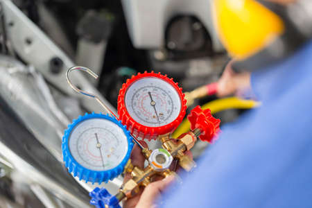 Repairman holding monitor tool to check and fixed car air conditioner system, Technician check car air conditioning system refrigerant recharge, Air Conditioning Repairの写真素材