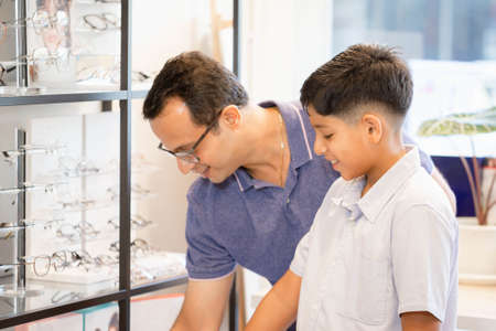 Indian father and son choosing eyeglasses in optics storeの写真素材