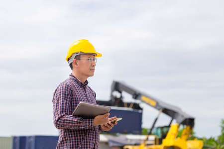 Foreman dock worker in hardhat and safety vest checking containers box from cargo, Engineer man with...