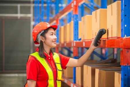 Warehouse worker with bar code scanner checking inventory, Female worker scanning boxes in warehouse rack, Workers working in warehouseの写真素材