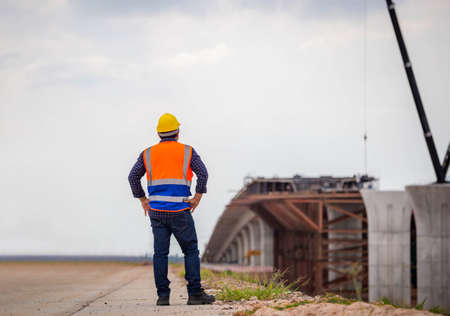 Back view of Construction engineer checking project at the building site, Foreman worker in hardhat at the infrastructure construction siteの写真素材